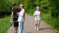 An elderly woman runs past a guy who is learning to walk with a walker. Rehabilitation after injuries and a healthy