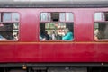 Elderly woman seated inside carriage and looking out of the window. Viewed from outside