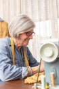 elderly woman sewing in front of a sewing machine with an expression of happiness Royalty Free Stock Photo
