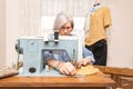 elderly woman sewing an orange cloth with an antique sewing machine Royalty Free Stock Photo