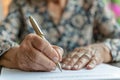 Elderly woman signing document, focus on hand with pen Royalty Free Stock Photo