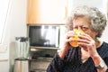 Elderly woman sips coffee in the kitchen of her home