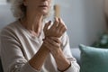 Elderly woman touches wrist check pulse counts heart rate closeup