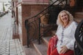 An elderly woman sits on steps in a European city. Retirement travels of old people around the world Royalty Free Stock Photo