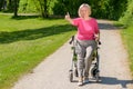 Elderly woman sits in wheeled walker on park path