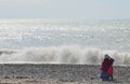 Elderly woman sitting on the beach during a storm and watching t