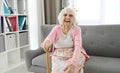 Elderly Woman Sitting On A Living Room Sofa Laughing And Looking Into The Camera