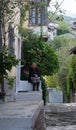 Elderly Woman Sitting on Low Concrete Whitewashed Wall in Albania