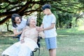 Elderly woman sitting in a wheelchair, smiling and happy with her daughter and grandson taking care of her Royalty Free Stock Photo