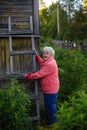 An elderly woman stands near her village house. Royalty Free Stock Photo