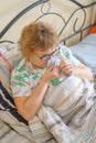 An elderly woman suffers from the flu and runny nose. The pensioner blows her nose in the nasal raft.
