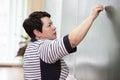 An elderly woman teacher writes with chalk