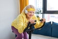 elderly woman training and doing exercise on cycle at home. sportive pensioner lifestyle
