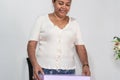 Elderly woman uncovering a cardboard box in the living room of her home