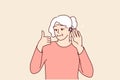 Elderly woman uses hearing aid and shows thumbs up confirming good sound volume thanks to new device