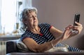 Elderly woman using mobile phone at home Royalty Free Stock Photo