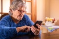 Elderly woman using a mobile phone over wood table at living room of home Royalty Free Stock Photo