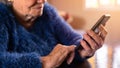 Elderly woman using mobile phone while sitting at living room home. Grandmother Royalty Free Stock Photo