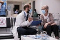 Elderly woman using wheelchair talking to geriatrician at clinic