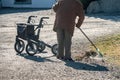 Elderly woman with walker, rakes the lawn and doing gardening work