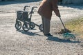 Elderly woman with walker, rakes the lawn and doing gardening work Royalty Free Stock Photo