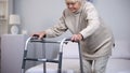 Elderly woman with walking frame, medical equipment using after trauma, hospital