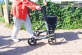 An elderly woman is walking while holding a walker