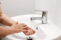 Elderly woman washes hand in bathroom