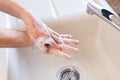 Elderly woman washing her hands with soap in a kitchen sink. Fingers spread. Personal hygiene for covid 19 infection prevention