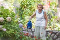 Elderly woman watering plants in her garden Royalty Free Stock Photo