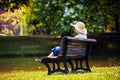 Elderly woman wearing a hat sitting on a wooden bench and relaxing at the park Royalty Free Stock Photo