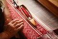 An elderly woman weaves fiber