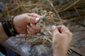 An elderly woman weaves a toy from the straw. Traditional Russian folk art