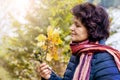 An elderly woman in the woods with pleasure examines a branch with oak leaves. Admiration of nature Royalty Free Stock Photo