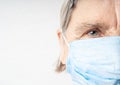 Elderly woman wrinkled face in protective medical mask.