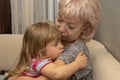 An elderly woman of 60-65 years old holds a small crying girl in her arms and calms her down. Concept: grandmother and granddaught