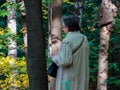 An elderly woman of 70 years touches the bark of trees in the autumn city Park