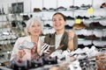 Elderly woman and young woman choosing sandals in shoe store Royalty Free Stock Photo
