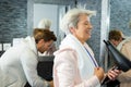 Elderly woman blowdrying hair in gym washroom