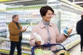 Elderly woman chooses milk in supermarket Royalty Free Stock Photo
