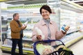 Elderly woman chooses milk in supermarket Royalty Free Stock Photo