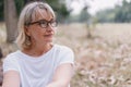 Elderly women caucasian wear glasses while sitting think at the public park in the autumn