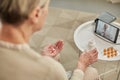 An elderly woman communicates remotely via a tablet with her doctor and takes medications according to his Royalty Free Stock Photo