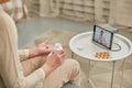 An elderly woman communicates remotely via a tablet with her doctor and takes medications according to his recommendations. Royalty Free Stock Photo