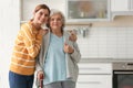 Elderly woman with female caregiver in kitchen.