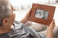 Elderly woman with framed family portrait