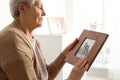 Elderly woman with framed family portrait at