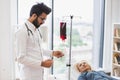 Elderly woman making blood transfusion looking at medical doctor in lab coat.