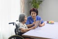 Elderly woman reading aloud a book for dementia therapy with caregiver