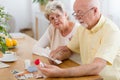 Elderly woman supporting sick senior man reading leaflet of drug